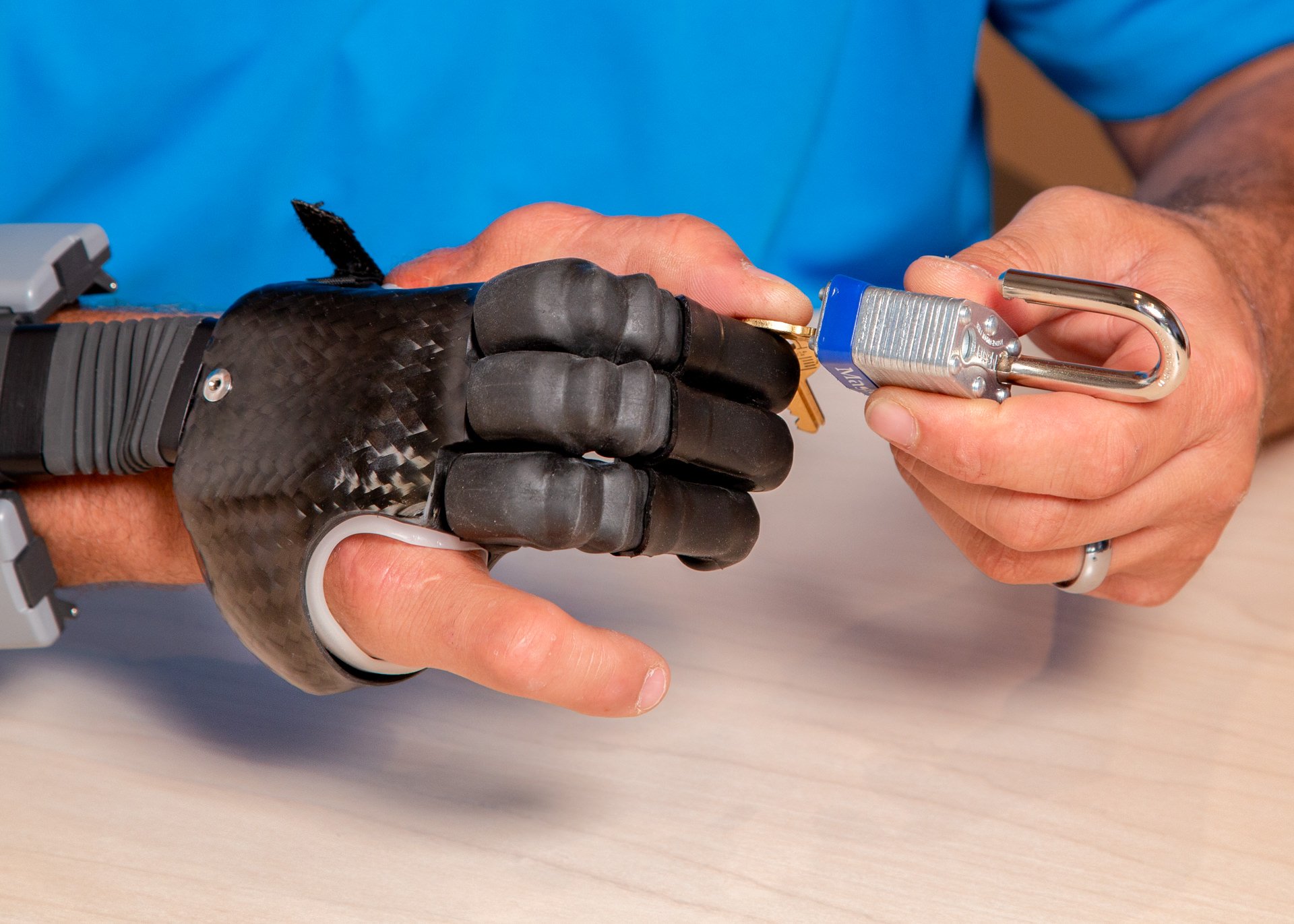 A partial hand patient uses electrically-powered i-digits to open a lock for a therapy exercise.