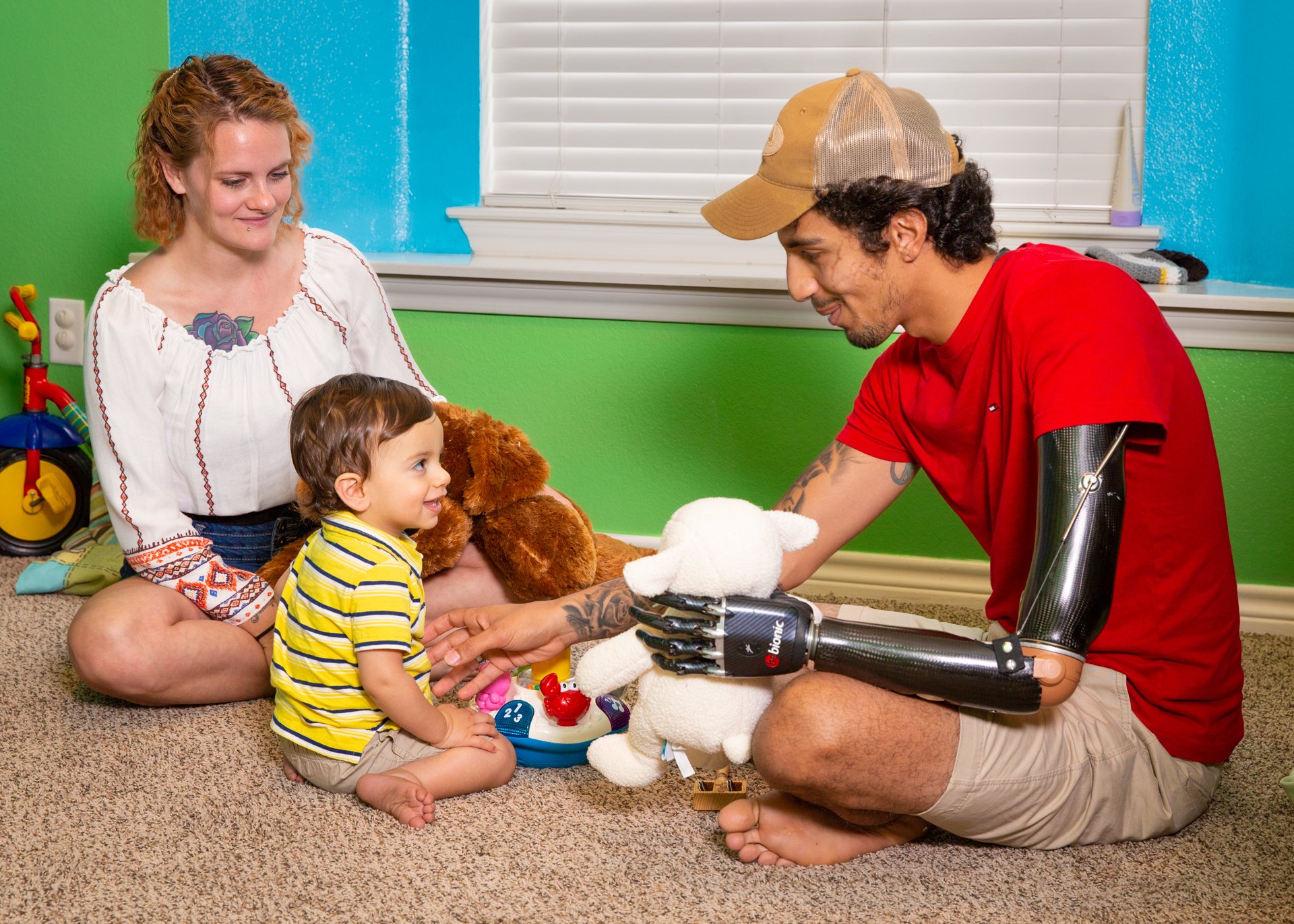 A high transhumeral patient uses a hybrid electrical and body-powered prosthesis to play with his family.