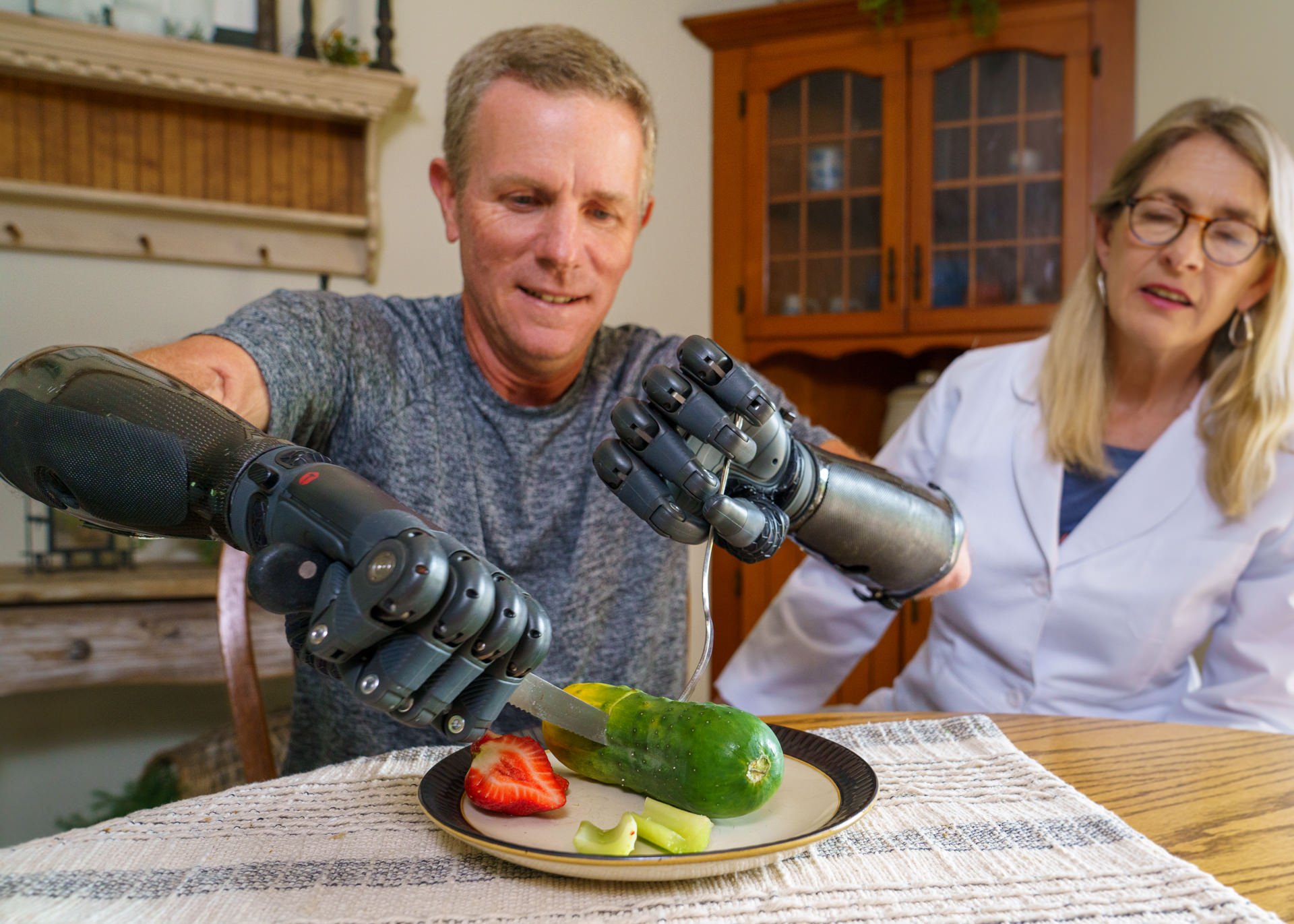 Gerry Kinney, a bilateral transradial patient, uses his TASKA myoelectric hands to cut food in a clinical therapy exercise.