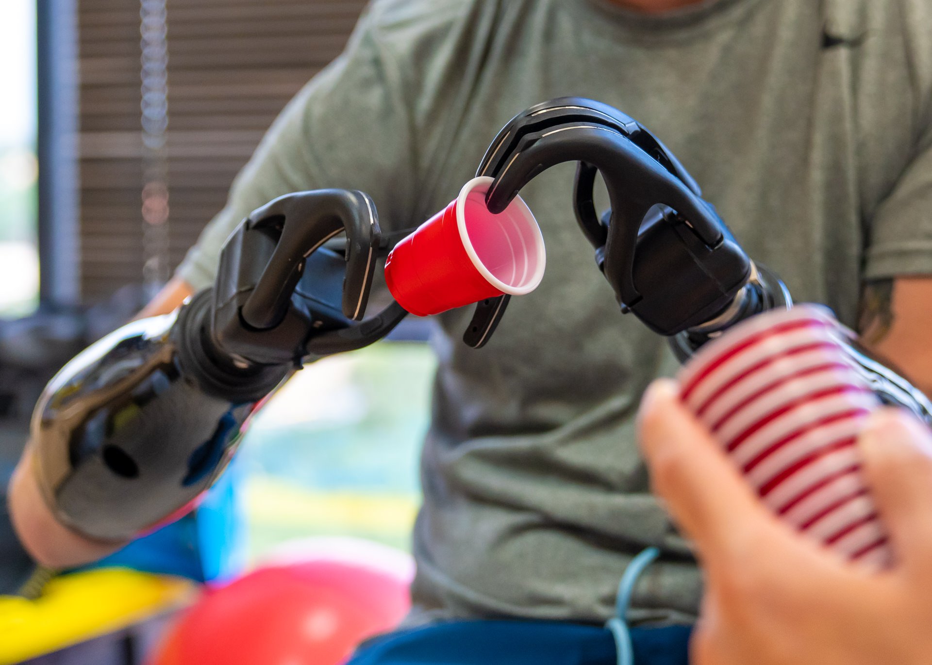 A bilateral transradial patient uses his ETD V2s to separate cups in a clinical therapy exercise.
