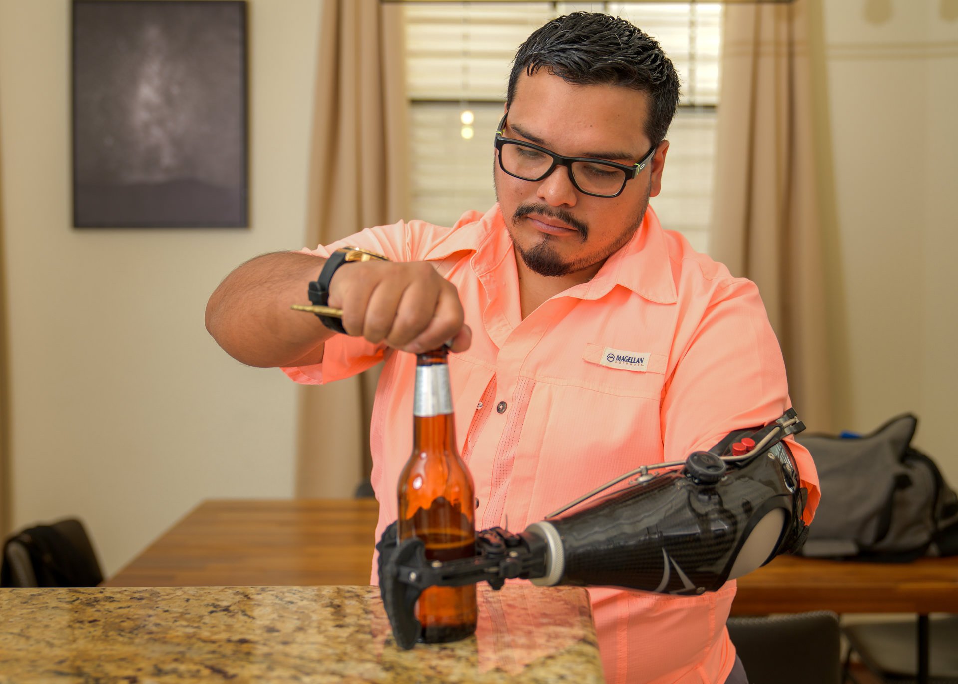 A transradial patient uses his body-powered V2P hook to assist in opening a beer bottle.