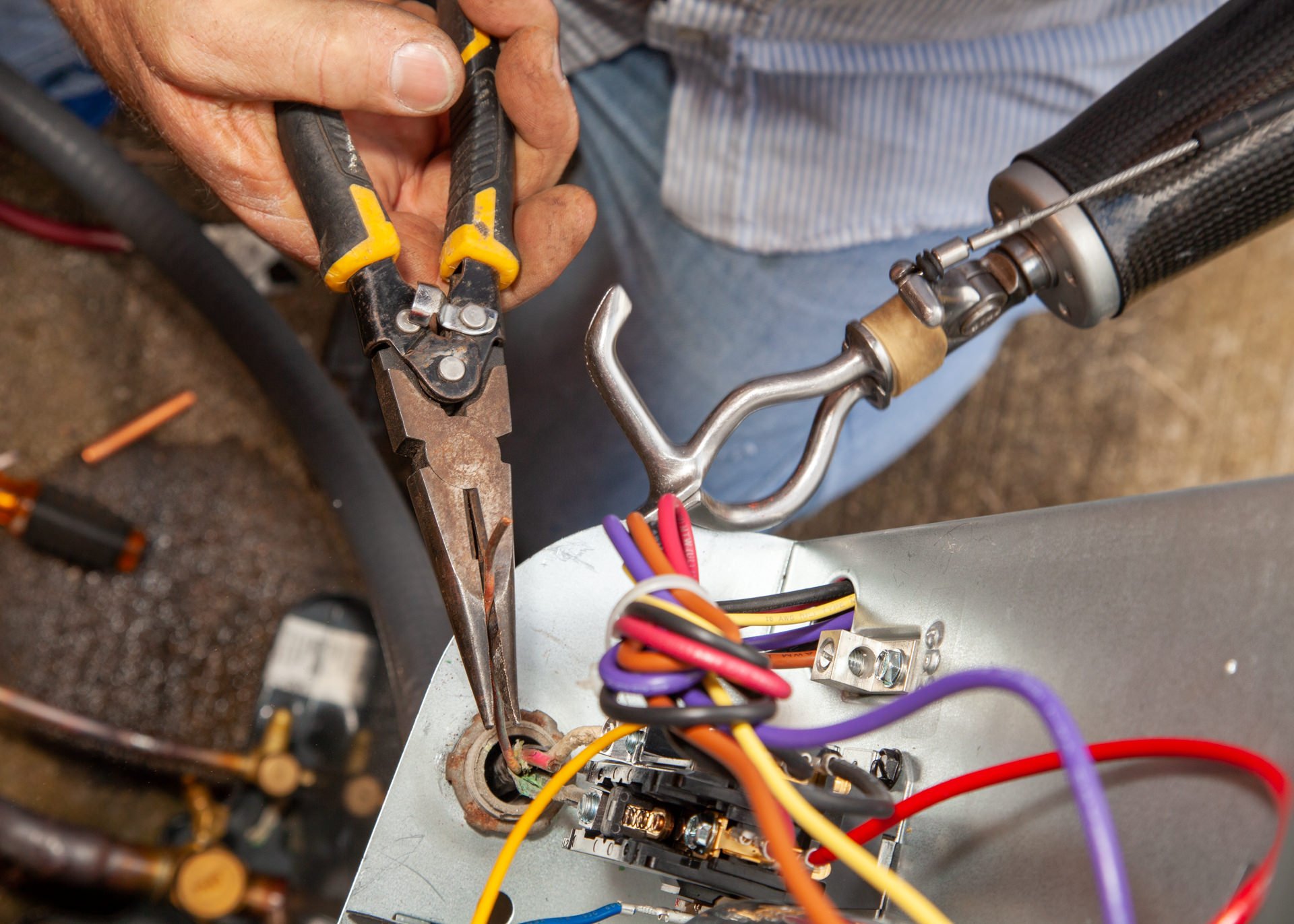 An electrician using his body-powered hook to repair an air conditioner