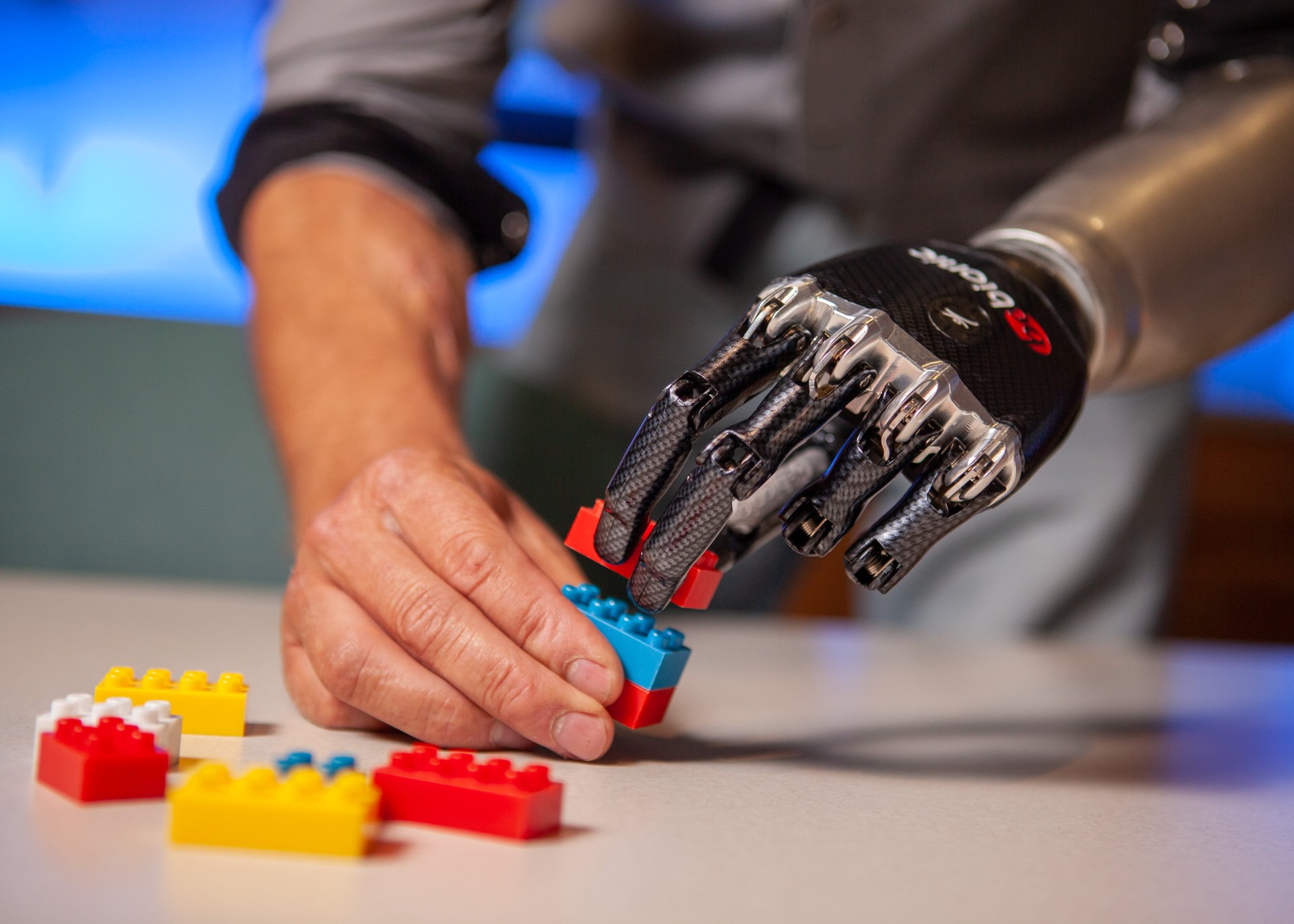 A transradial patient uses a myoelectric hand to stack legos.