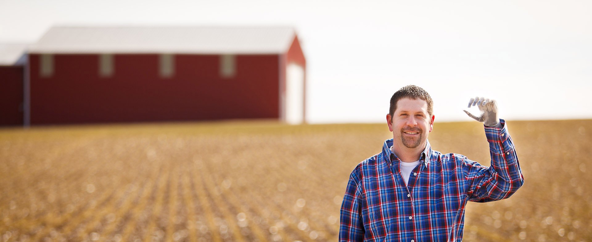 Jason Koger waving in field with Touch Bionics i-limb hands