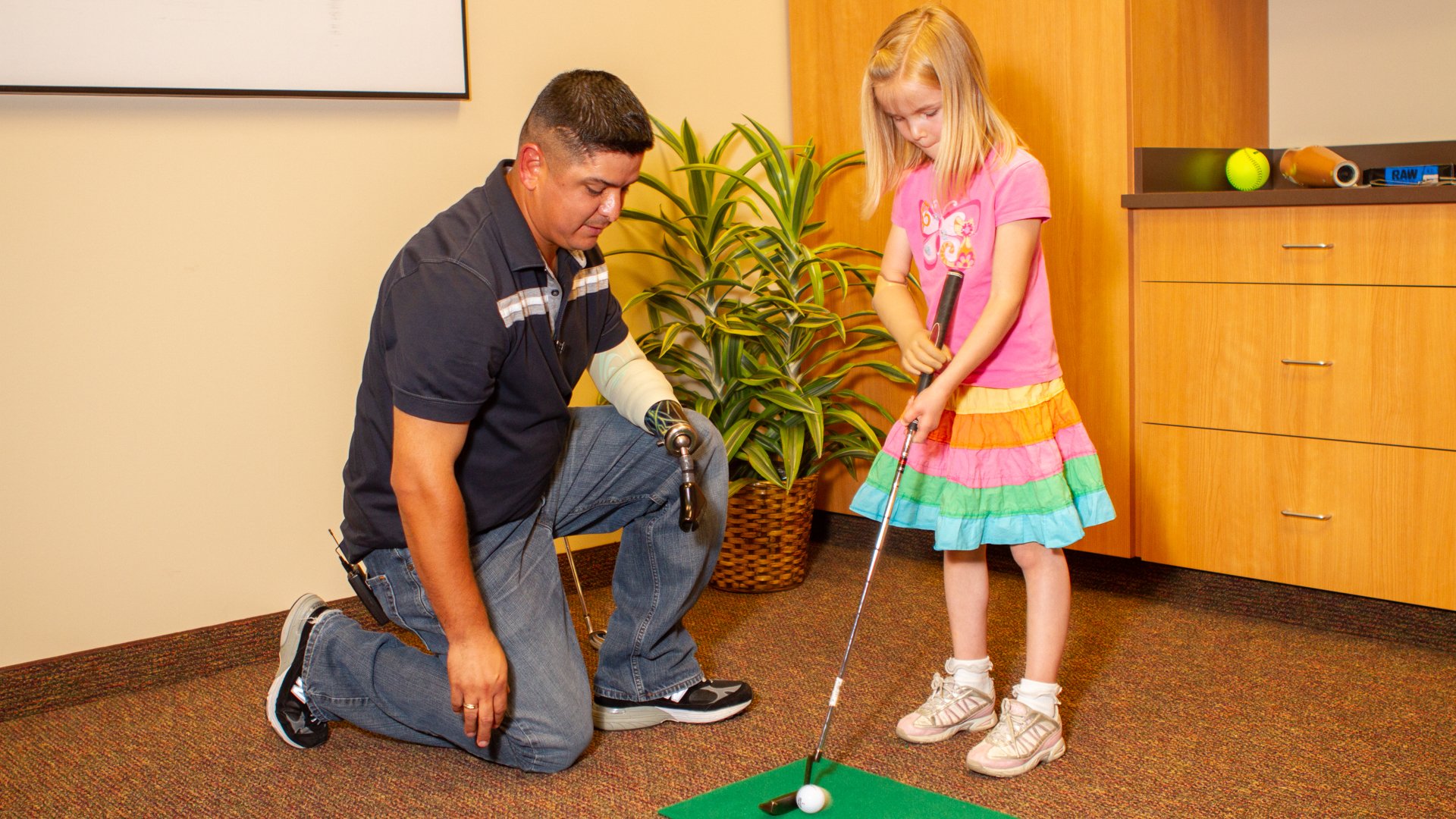 While in town on an event, Ramon Padilla works with pediatric patient Amber Peterson at her golf game.